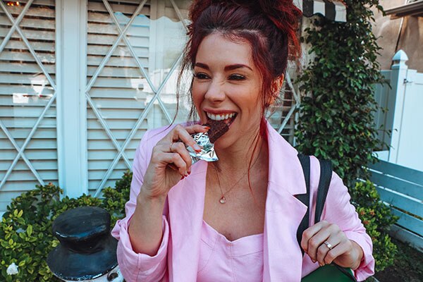 A smiling woman enjoying a Special-K breakfast bar.