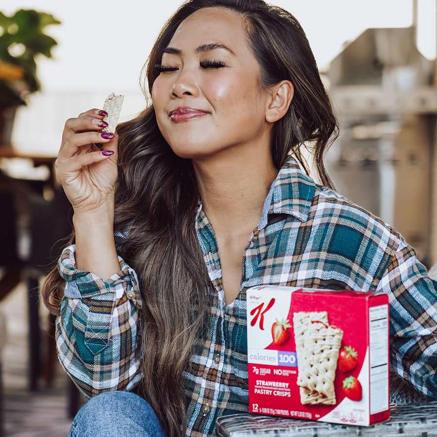 A smiling woman enjoying a Special-K breakfast bar.